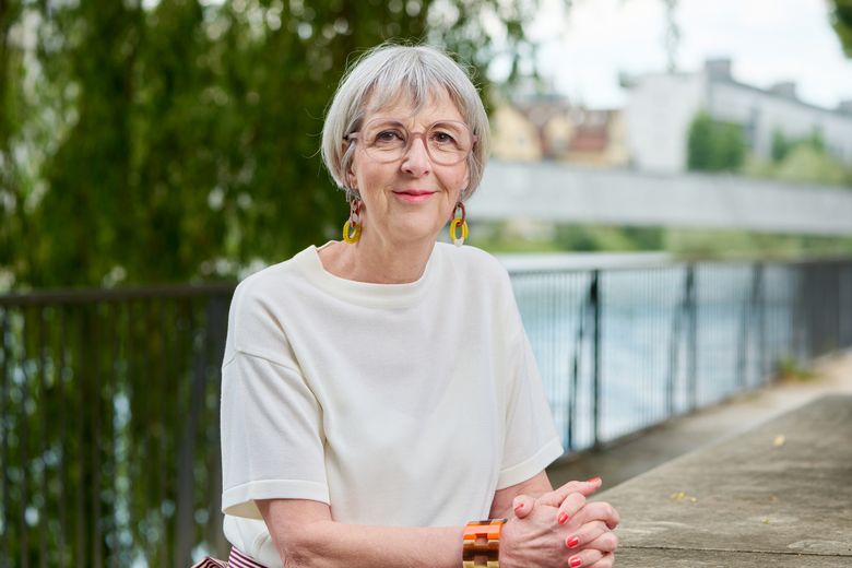 Frau mit grauem Haar sitzt am Fluss.
