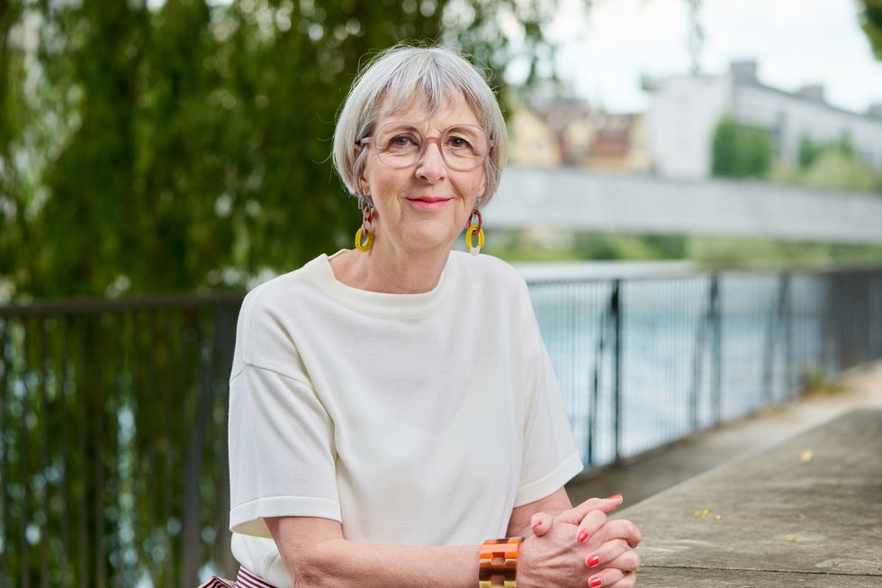 Frau mit grauem Haar sitzt am Fluss.