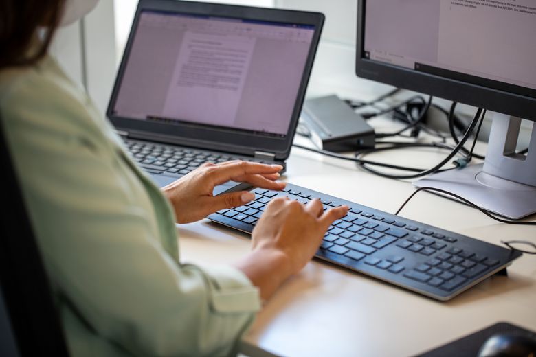 Eine Frau sitzt am Schreibtisch, vor ihr zwei Bildschirme. Sie tippt etwas auf der Tastatur. Foto: istock/alvarez 