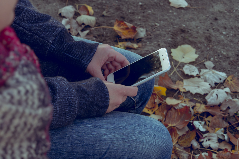 Eine Nahaufnahme zeigt die Hände einer Person, die ein Smartphone halten.