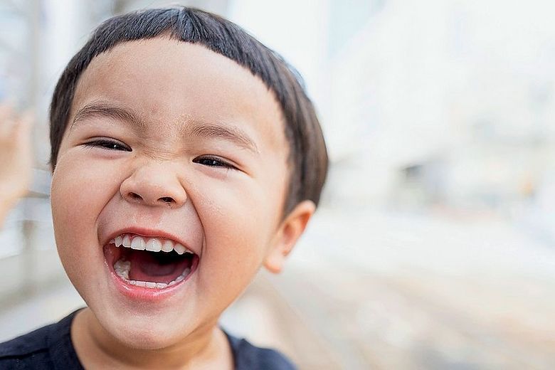 Ein Kind lacht in die Kamera. Foto: Unsplash/kazuend