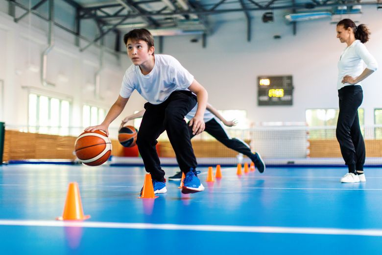 Ein Jugendlicher dribbelt einen Basketball in einer Turnhalle.
