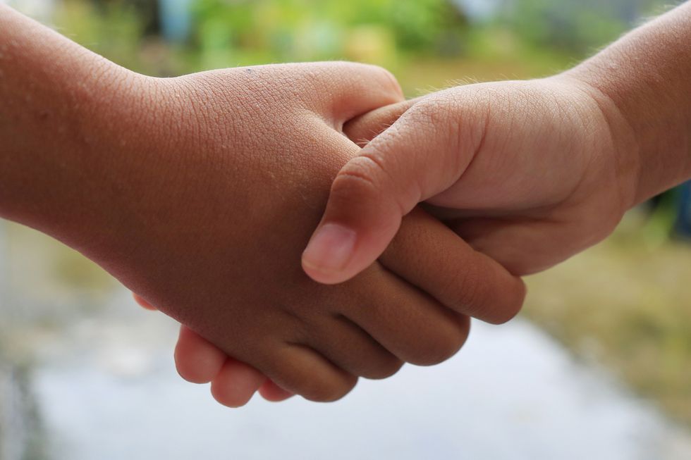 Zwei Kinder reichen sich die Hand.