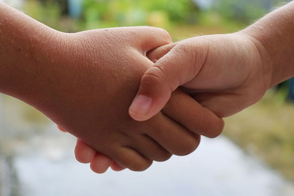 Zwei Kinder reichen sich die Hand.