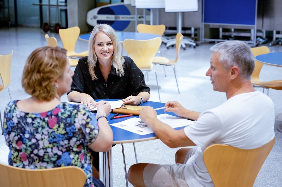 Zwei Frauen und ein Mann sitzen am Tisch und unterhalten sich.