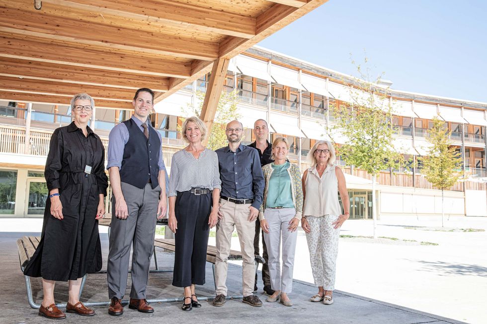 Die Geschäftsleitung LCH steht in einem sonnigen Schulhof.