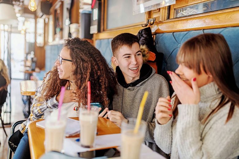 Jugendliche sitzen plaudernd in einem Strassen-Cafe.