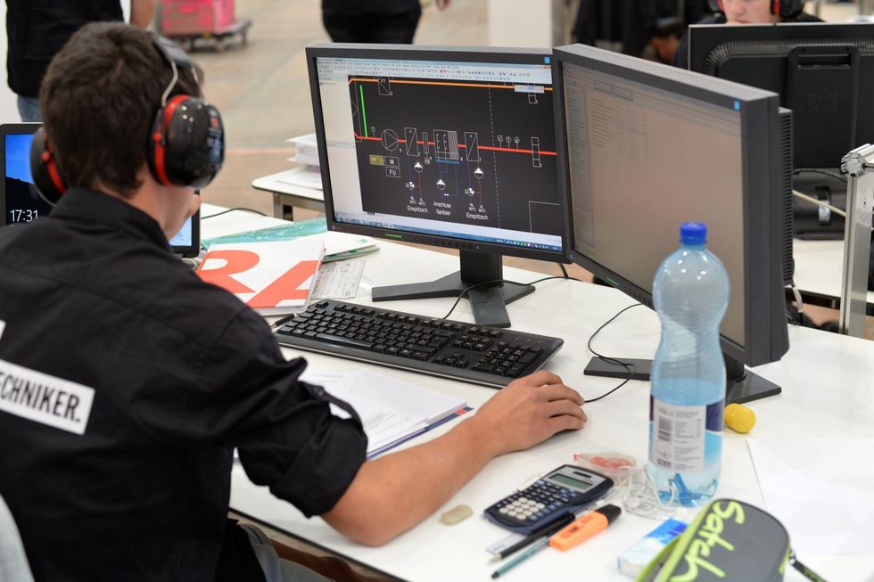 Lehrling an zwei Bildschirmen bei der Arbeit