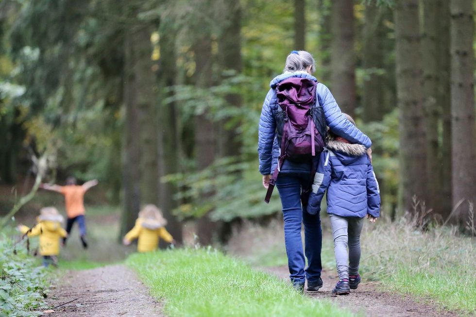 Eine Frau und ein Kind spazieren im Wald.