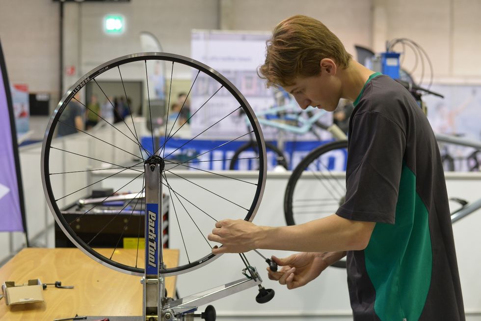 Lernender spannt die Speichen und zentriert damit ein Velorad
