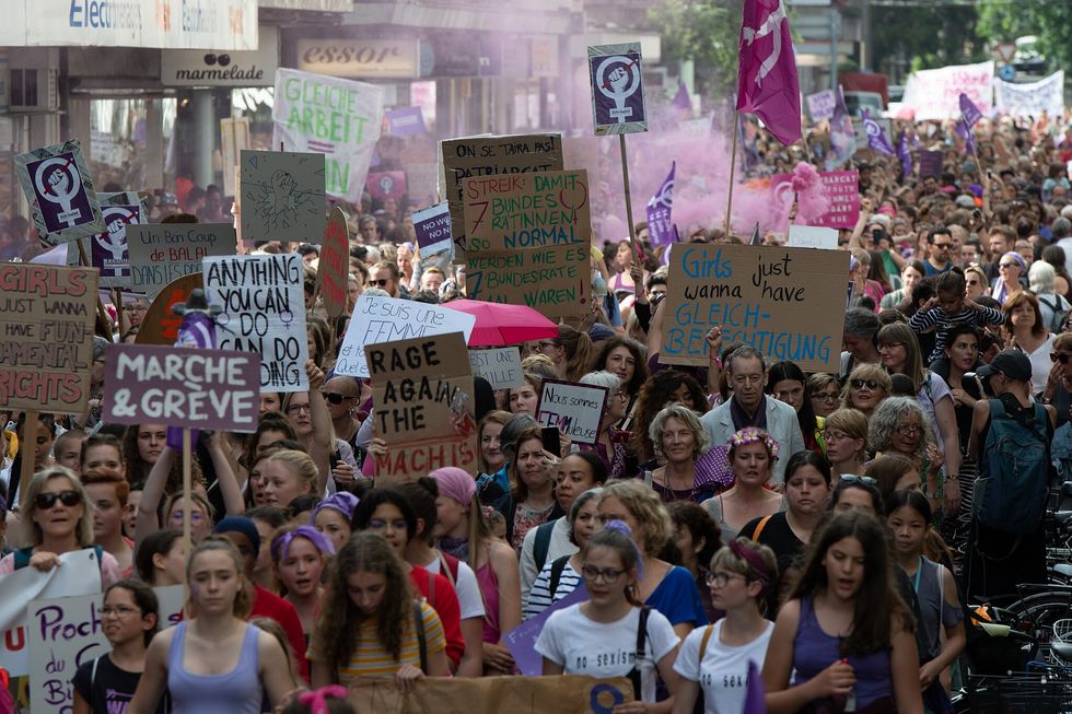 Viele Frauen gehen gemeinsam auf einer Strasse. Sie halten zum Teil Schilder und Banner hoch, auf denen Botschaften für die Anliegen des feministischen Streiks zu lesen sind.