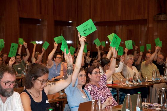 Delegiert halten grüne Stimmzettel in die Höhe.