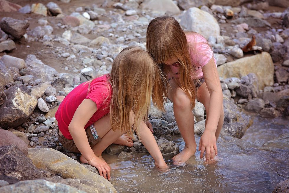 Zwei Mädchen suchen in einem Bergbach nach Steinen.