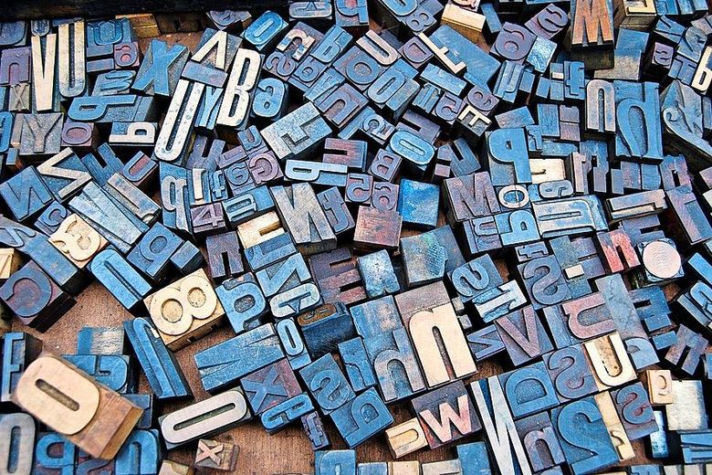 Das Alphabet in Form von Druckstempeln liegt verstreut auf einem Tisch. Foto: Unsplash/Amador Loureiro