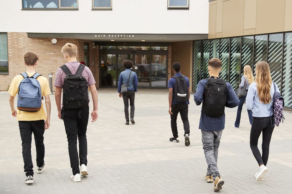 Schülerinnen und Schüler überqueren den Pausenhof in Richtung Schuleingang.