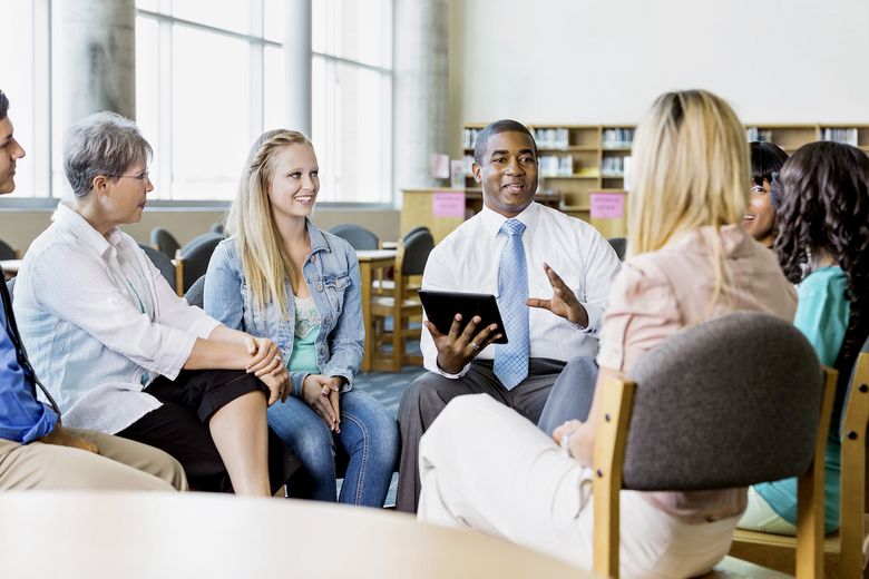 Man leading discussion group of adults and teens