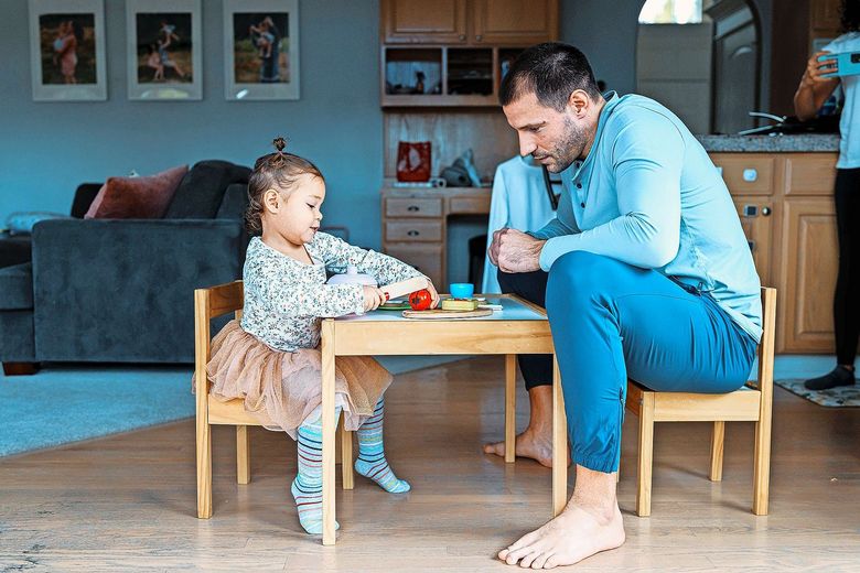 Ein Vater sitzt mit seinem Kind an einem Spieltisch.