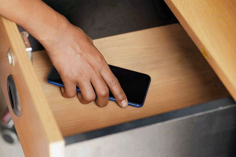 Ein Handy wird in der Schublade versorgt.