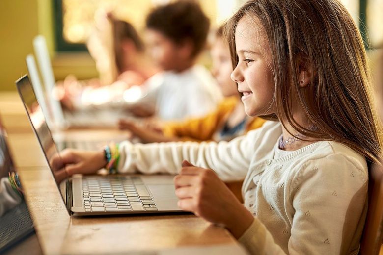 Schulmädchen sitzt vor einem Computer.