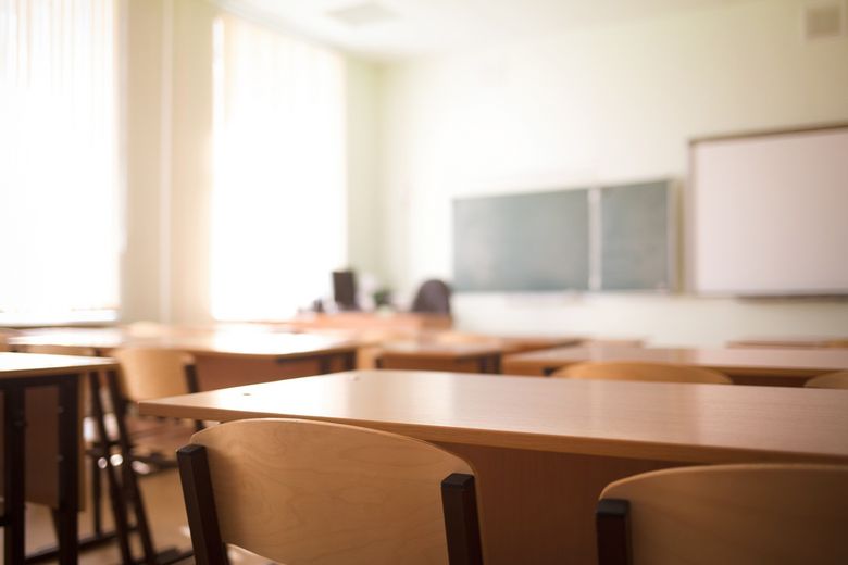 Schulzimmer mit Blick auf ein leeres Lehrerpult.