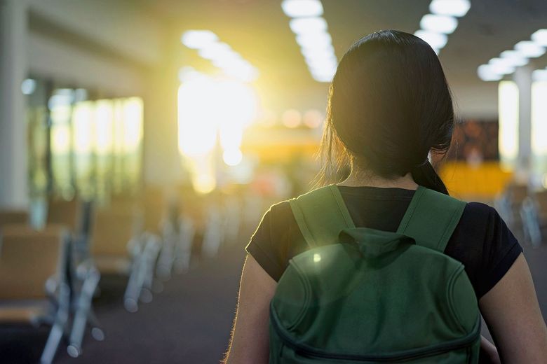 Schulmädchen mit Rucksack von hinten fotografiert.