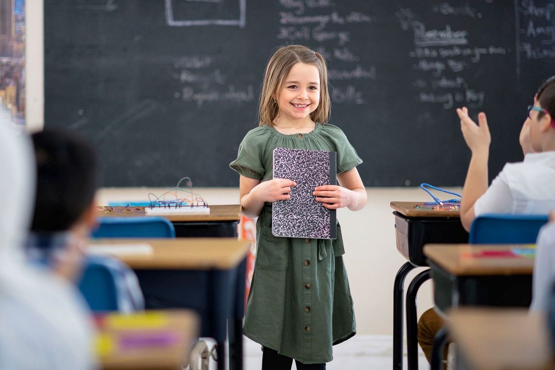 1188253785 Ein Mädchen hält vor der Klasse einen Vortrag und lächelt.