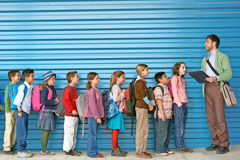 Ein Lehrer hat die Klasse vor sich in einer Reihe und zählt, ob alle da sind.