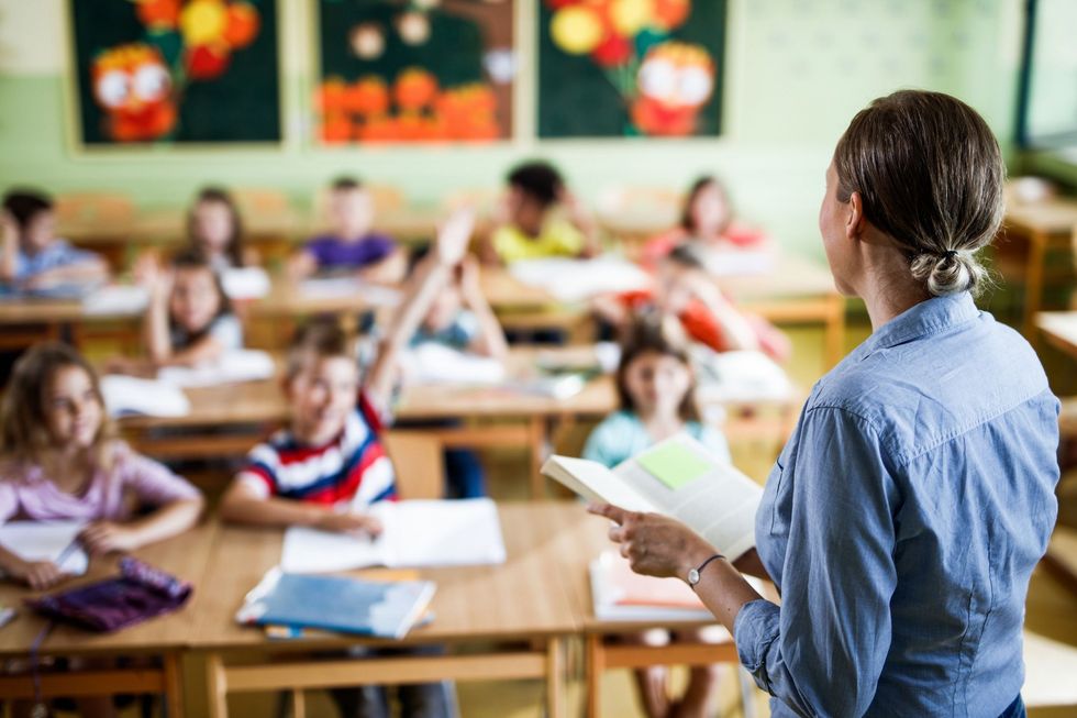 Eine Lehrerin steht vor der Schulklasse.