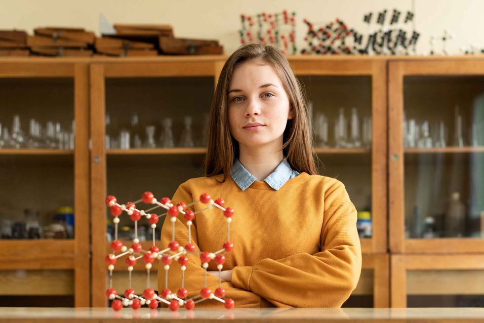 Mädchen steht selbstbewusst vor einem Molekül-Modell