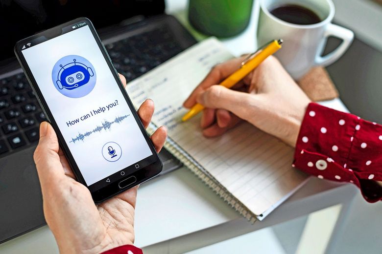 Eine Hand hält das Smartphone mit einem Chatbot, die andere Hand macht Notizen.
