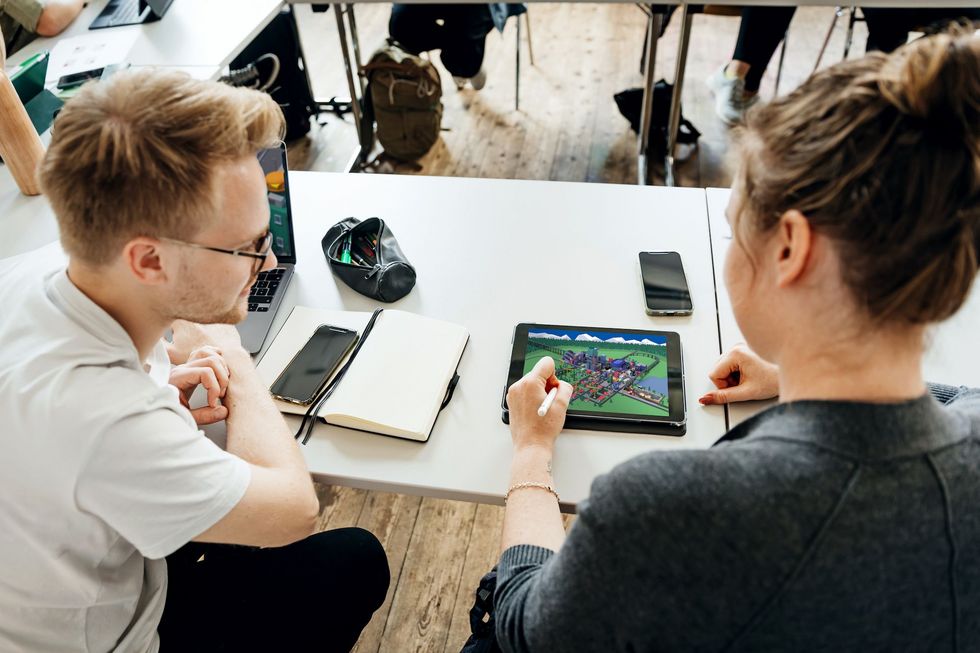 Zwei Menschen schauen auf ein Tablet.