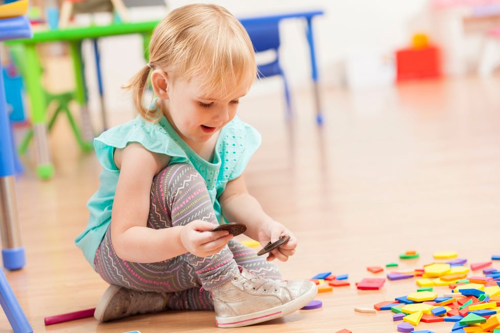 Ein kleines Mädchen spielt mit einem Puzzle in einer Kita.