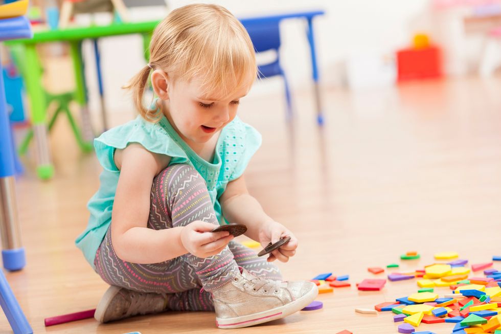 Ein kleines Mädchen spielt mit einem Puzzle in einer Kita.