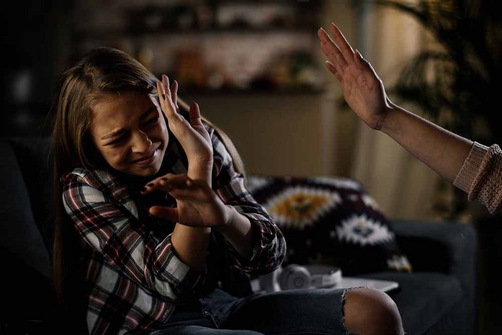 1216323731 Mädchen hält sich schützend die Hand vors Gesicht. Die Mutter will sie ohrfeigen.