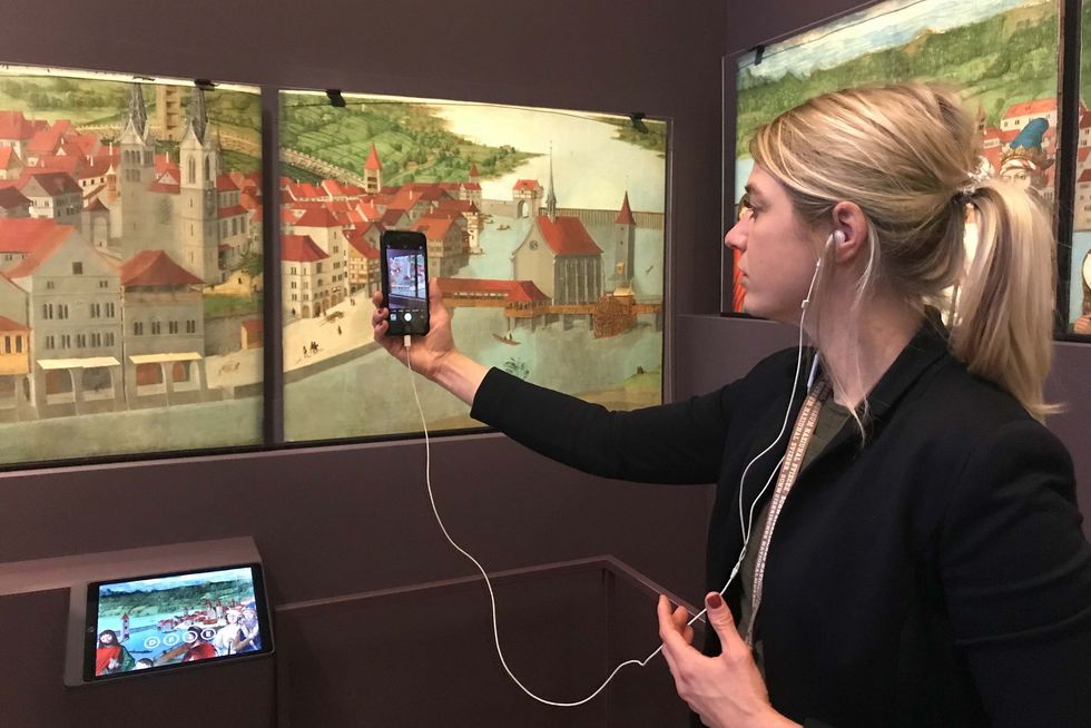 Vermittlungsperson steht im Landesmuseum vor einem Bild zur Schweizer Geschichte
