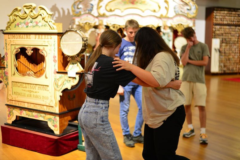 Zwei Mädchen tanzen zur Musik eines alten Automaten.