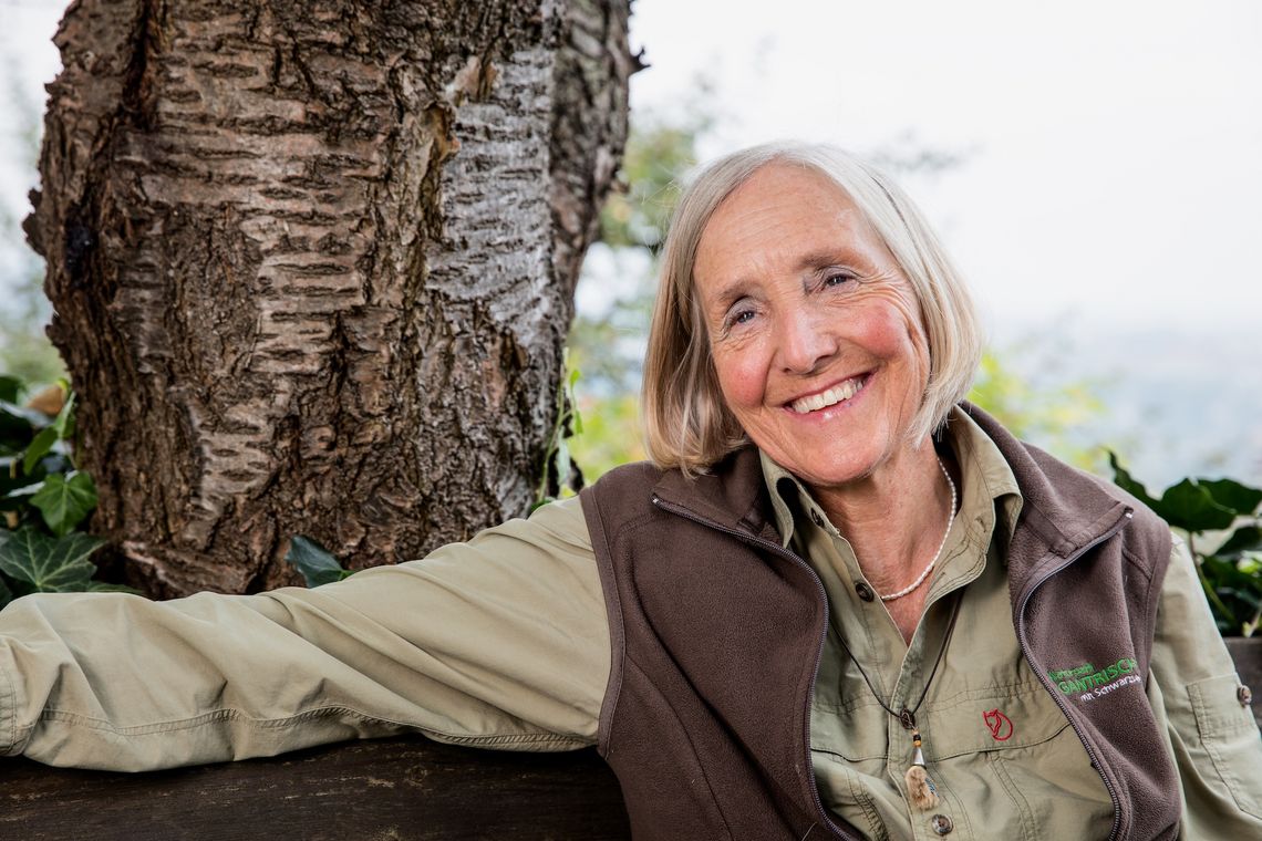 Eine Frau sitzt lächelnd auf einer Bank.