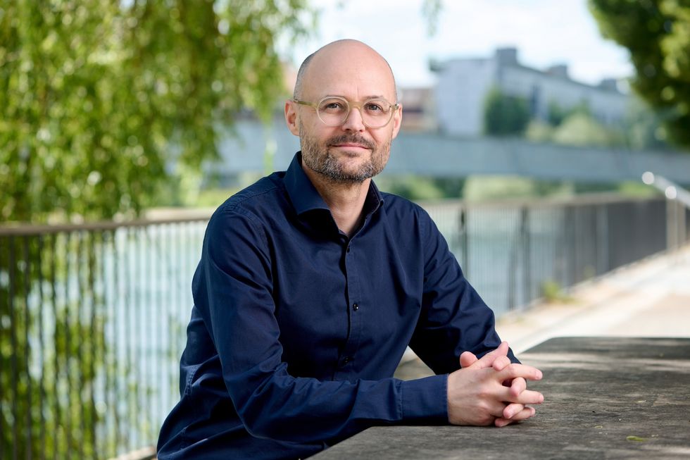 Ein Mann sitzt mit gefalteten Händen an der Limmat