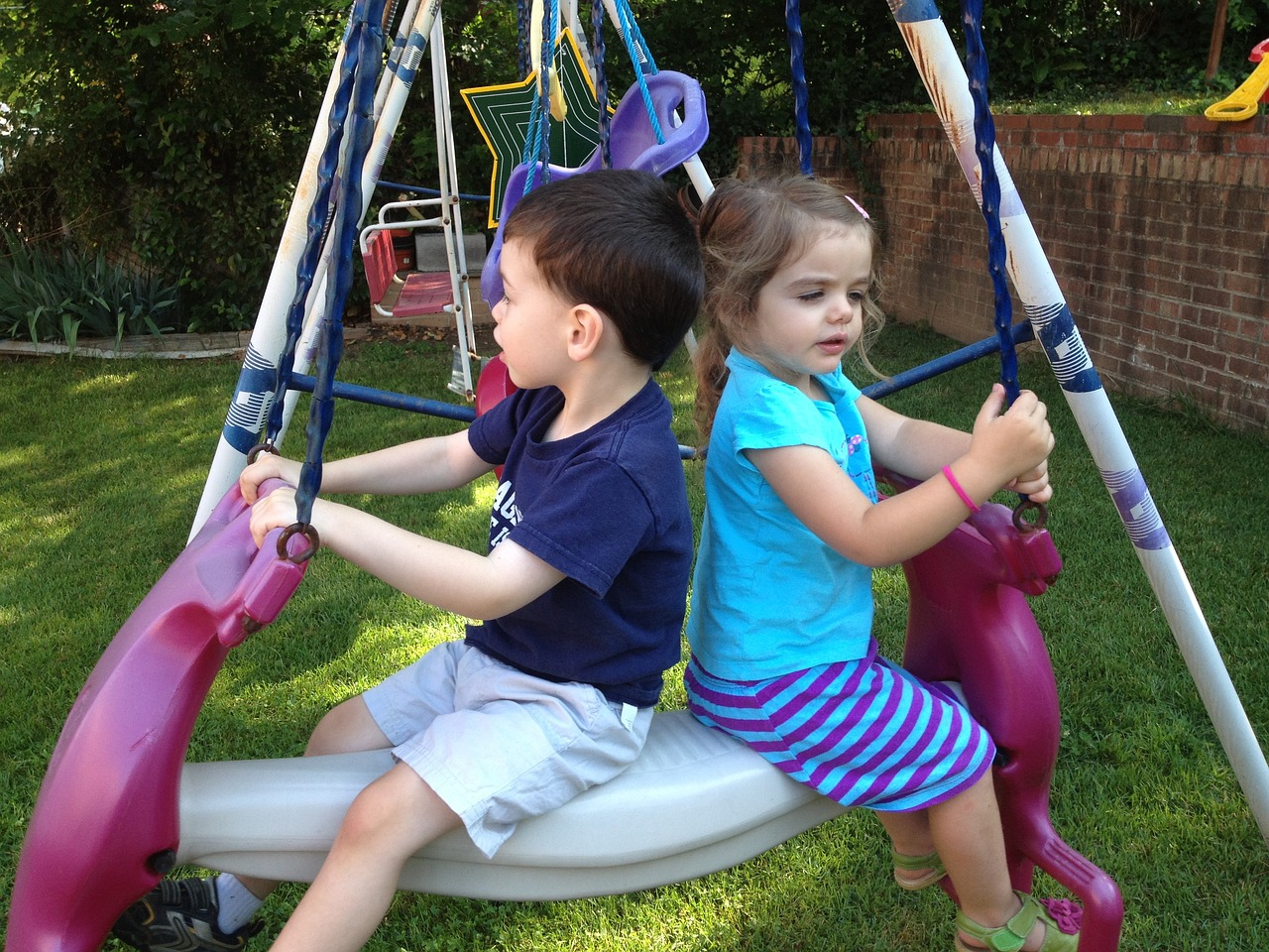 Zwei kleine Kinder auf einer Schaukel auf einem Spielplatz.